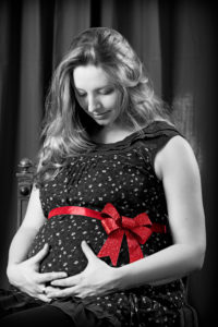 Babybauch mit roter Schleife