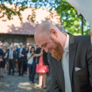 Hochzeit am Mühlenhof Münster - Bräutigam mit Gesellschaft im Hintergrund Hochzeit am Mühlenhof Münster - Gesellschaft im Hintergrund